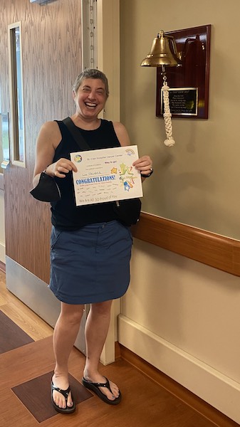 Lisa holding a certificate, next to a bell